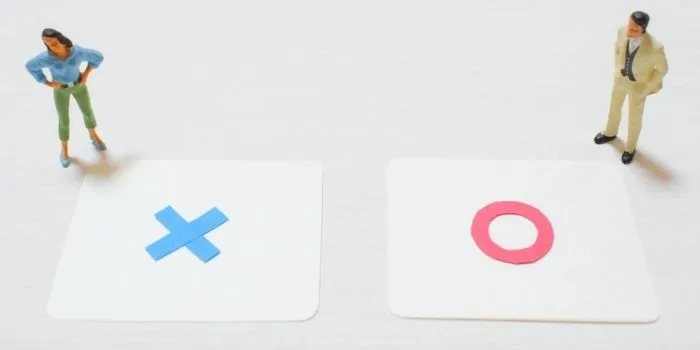 丸とバツが書かれた紙の上に立つミニチュア