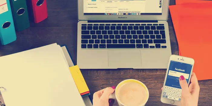 パソコンの前でスマホを見る人